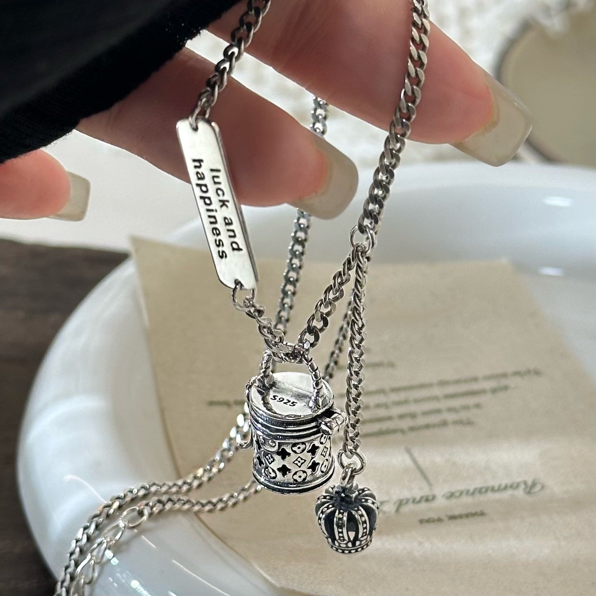 The S925 sterling silver monogram bucket bag necklace can be unlocked, with a pendant, hollow crown, niche design, and a light luxury and high-end necklace